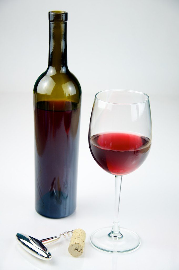Glass of Red Wine with a bottle of Red Wine shot on a white background.